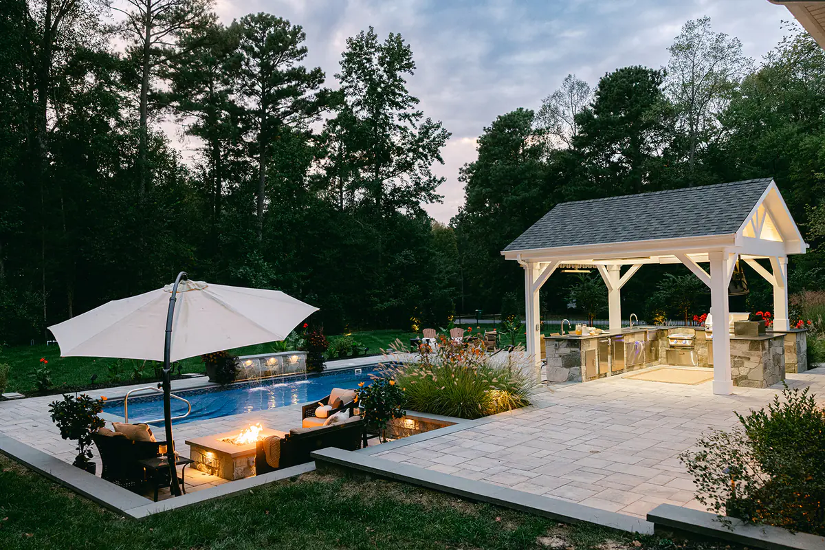 backyard at night with pool firepit and pavilion
