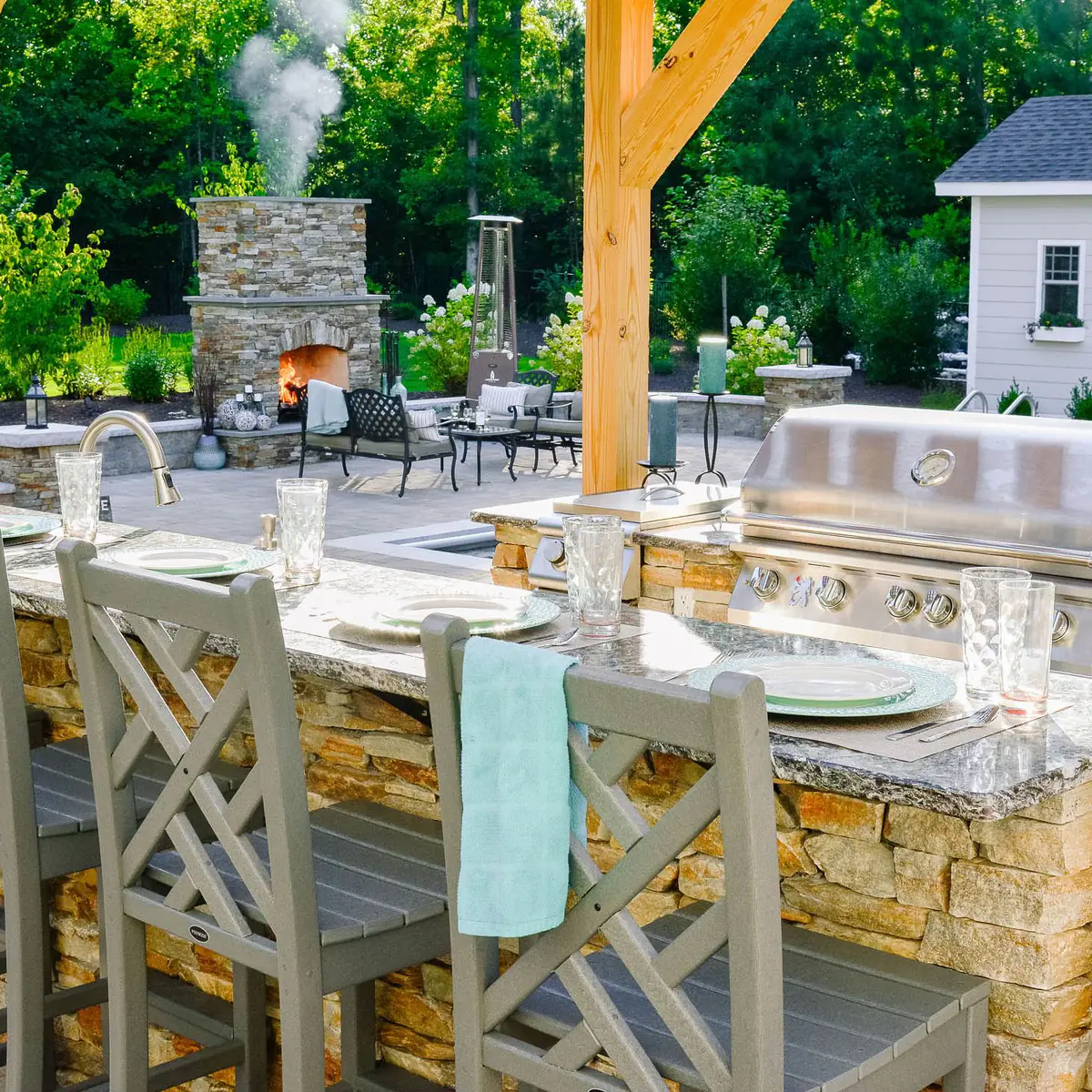 Smoke billowing from outdoor fireplace near outdoor kitchen