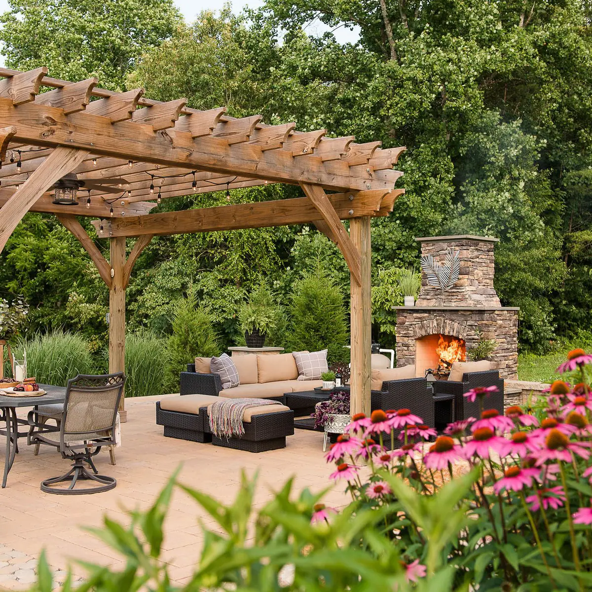 paver patio with pergola, outdoor fireplace, and native landscaping
