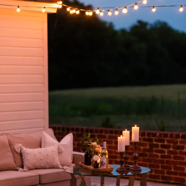 Elegant lounge area on travertine patio with string lights and brick sitting wall