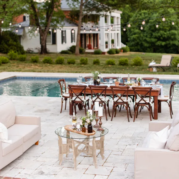 Elegant pool party with dining and lounge setup on travertine patio