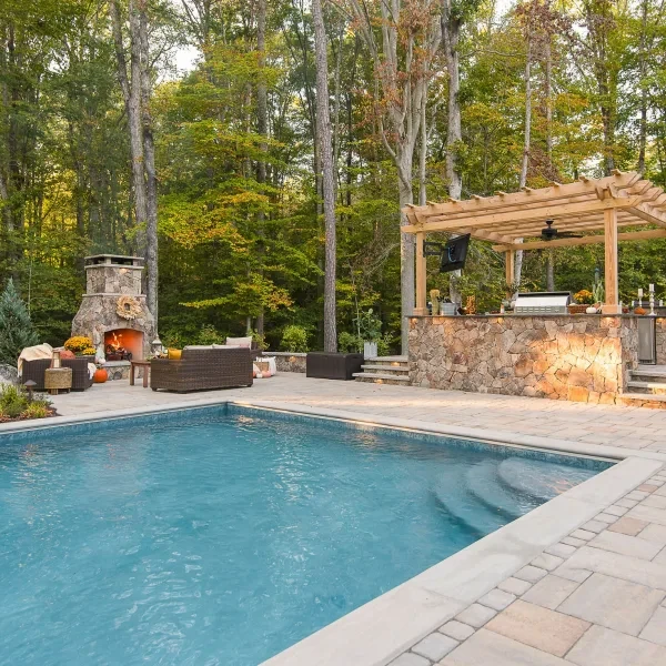 Installed fiberglass pool in backyard patio nearby the fireplace and pergola