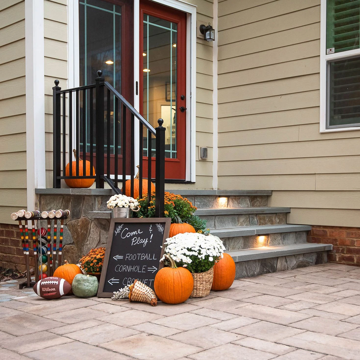 stone steps leading from paver patio to the back door and decorated for fall with pumpkins, football and croquet
