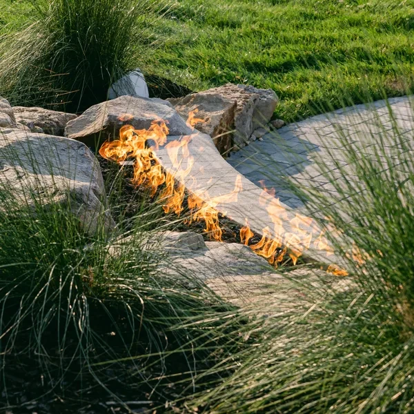 Dual fire bowls with bold flames on limestone caps and Terra Cut facing