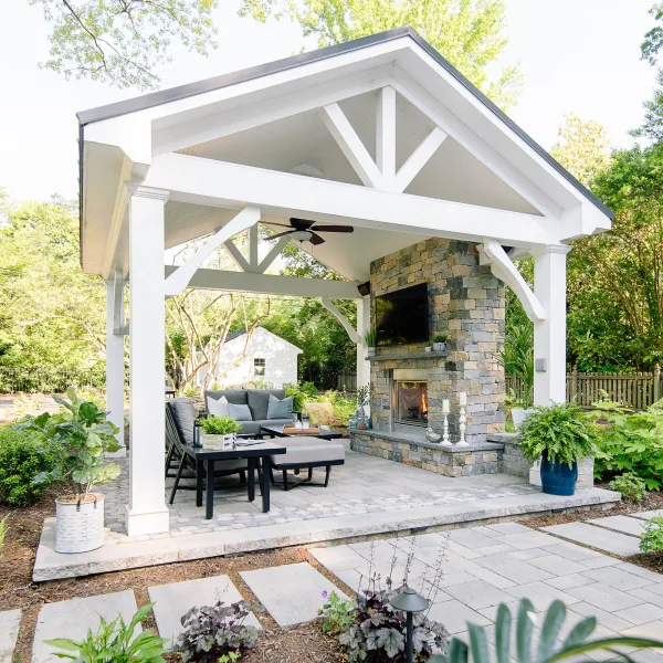 Cozy backyard paver patio with a large fireplace and sitting area under white pavilion