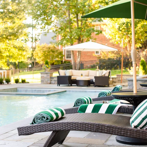 Green striped towels rolled up on lounge chairs by the pool