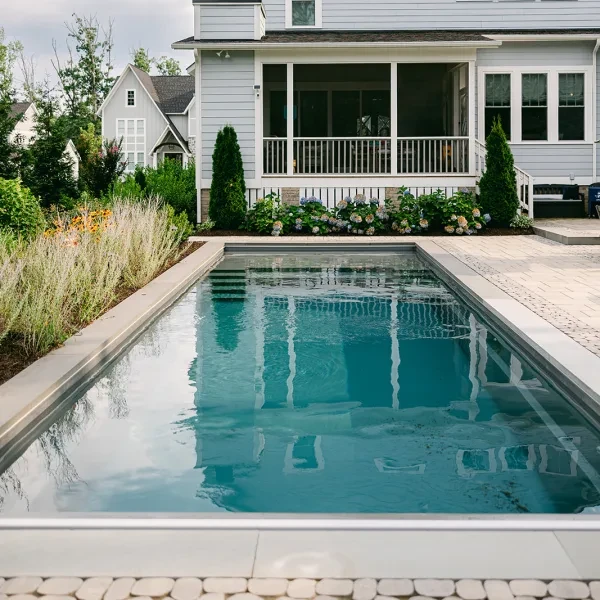 Rectangular backyard pool with safety cover and soft garden backdrop