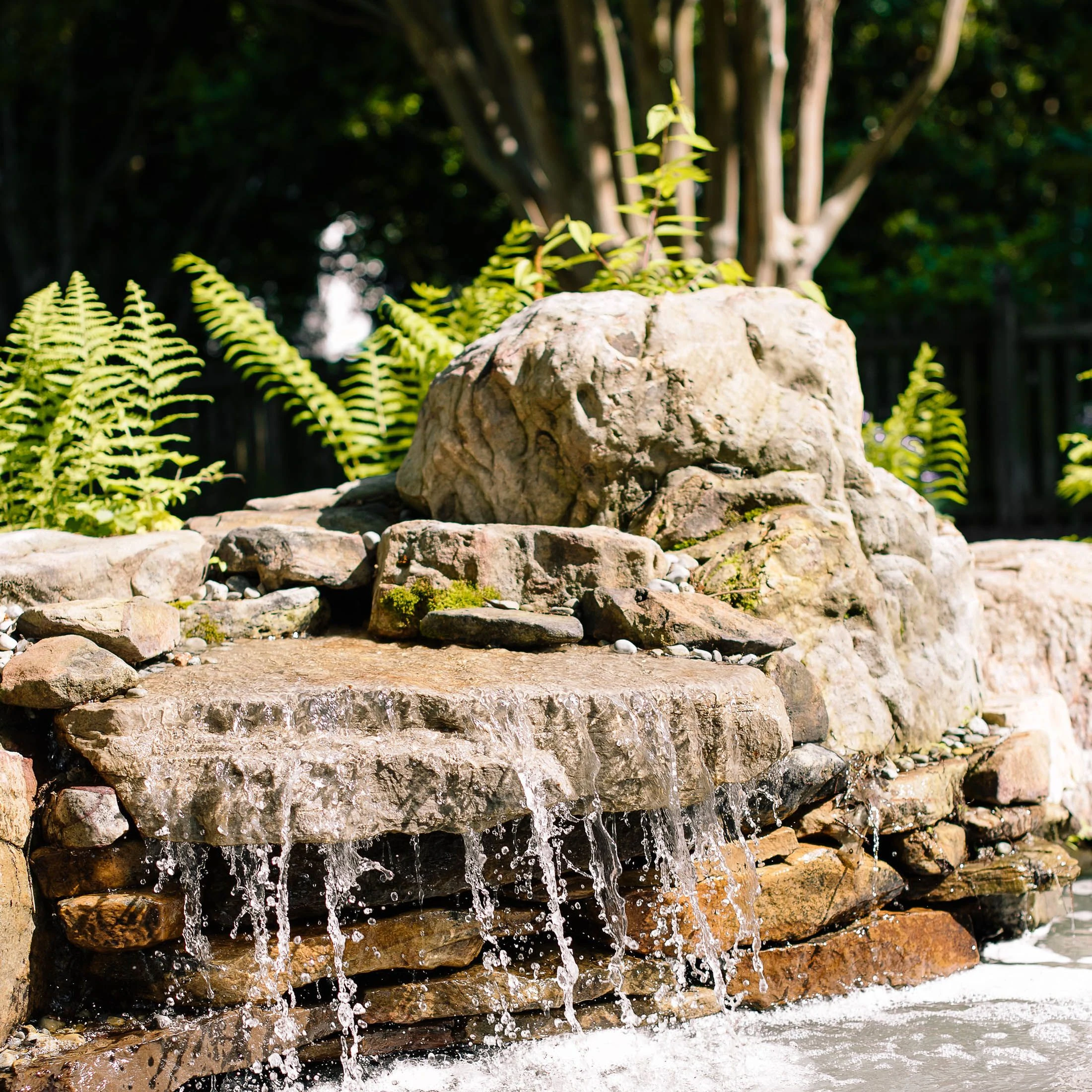 Stacked stone waterfall installed next to backyard pond