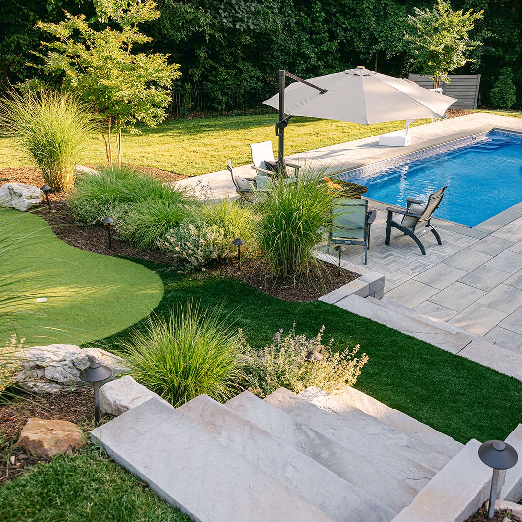 fiberglass swimming pool with concrete pavers and putting green