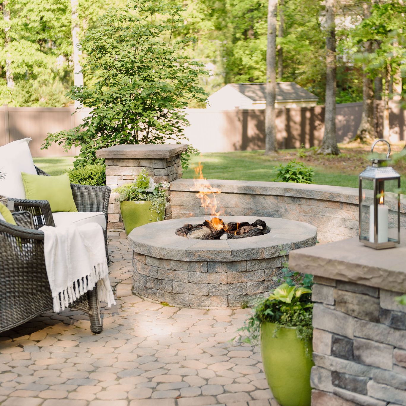 Gas fire pit with sitting wall and pillars on a paver patio.