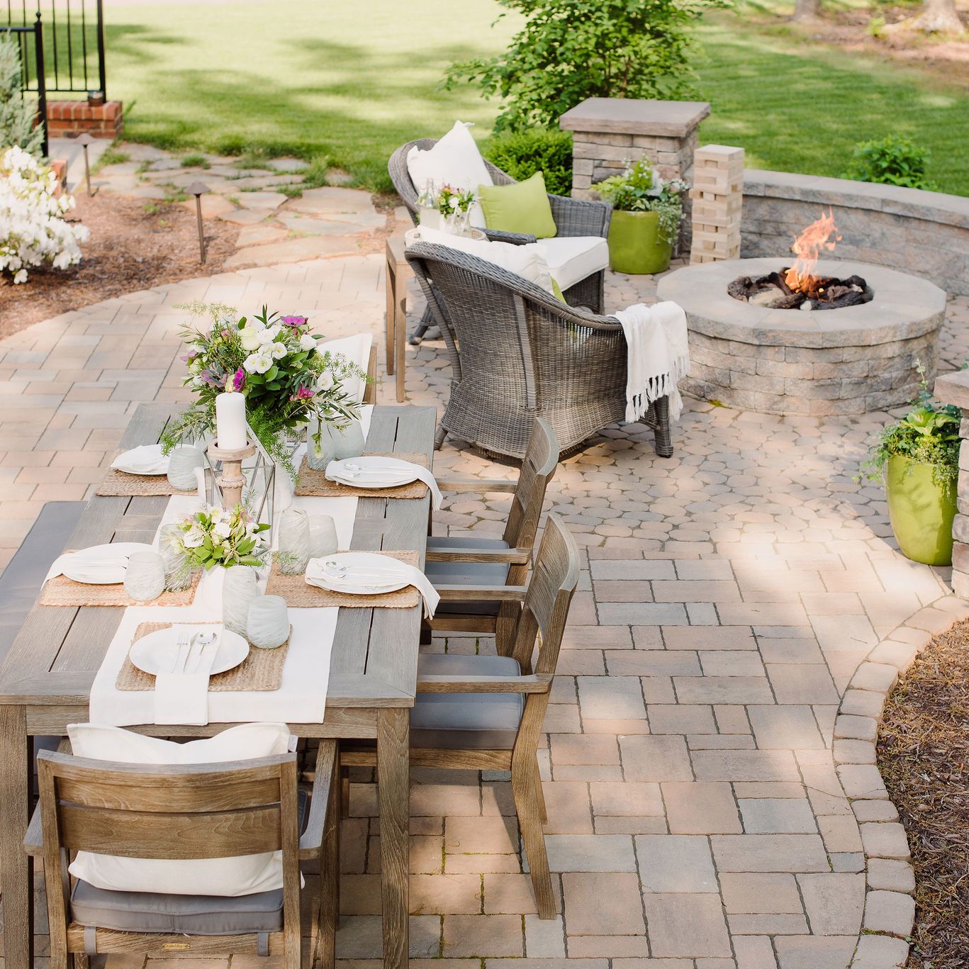 Techo-Bloc paver patio with outdoor dining table, gas fire pit, sitting wall, and pillars.