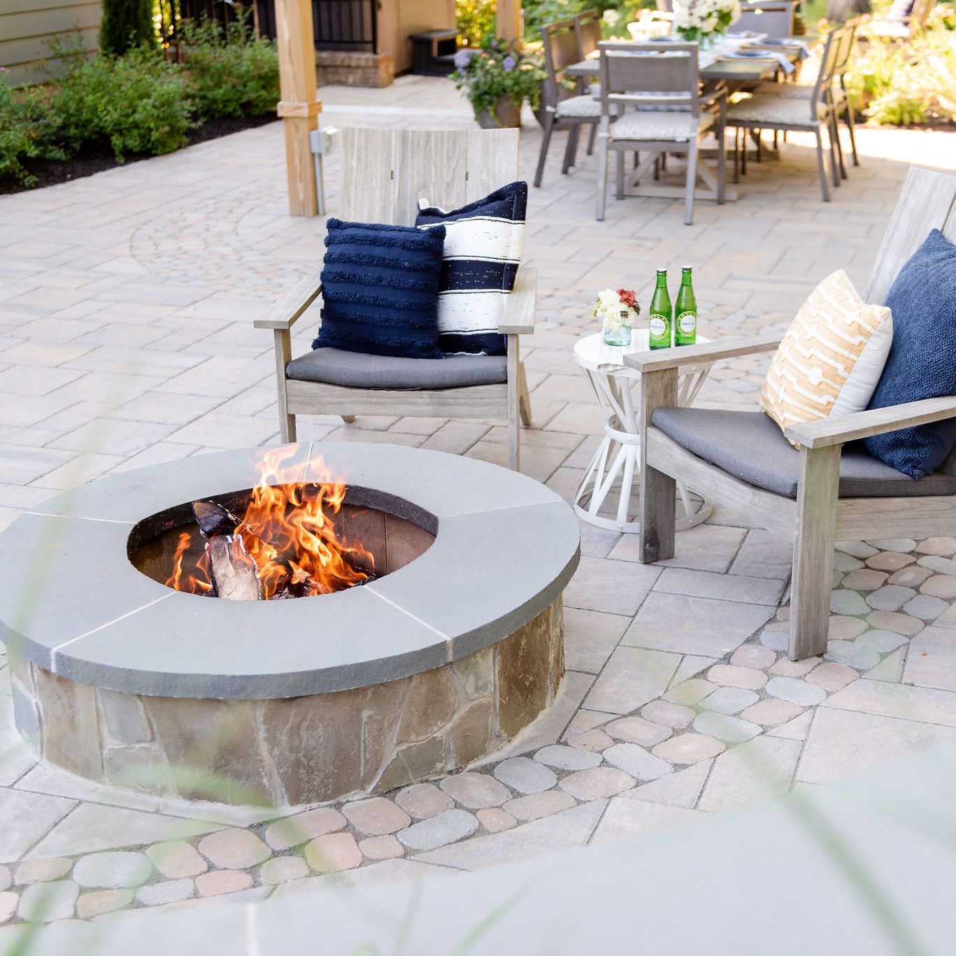 Stone fire pit on a paver patio with two chairs