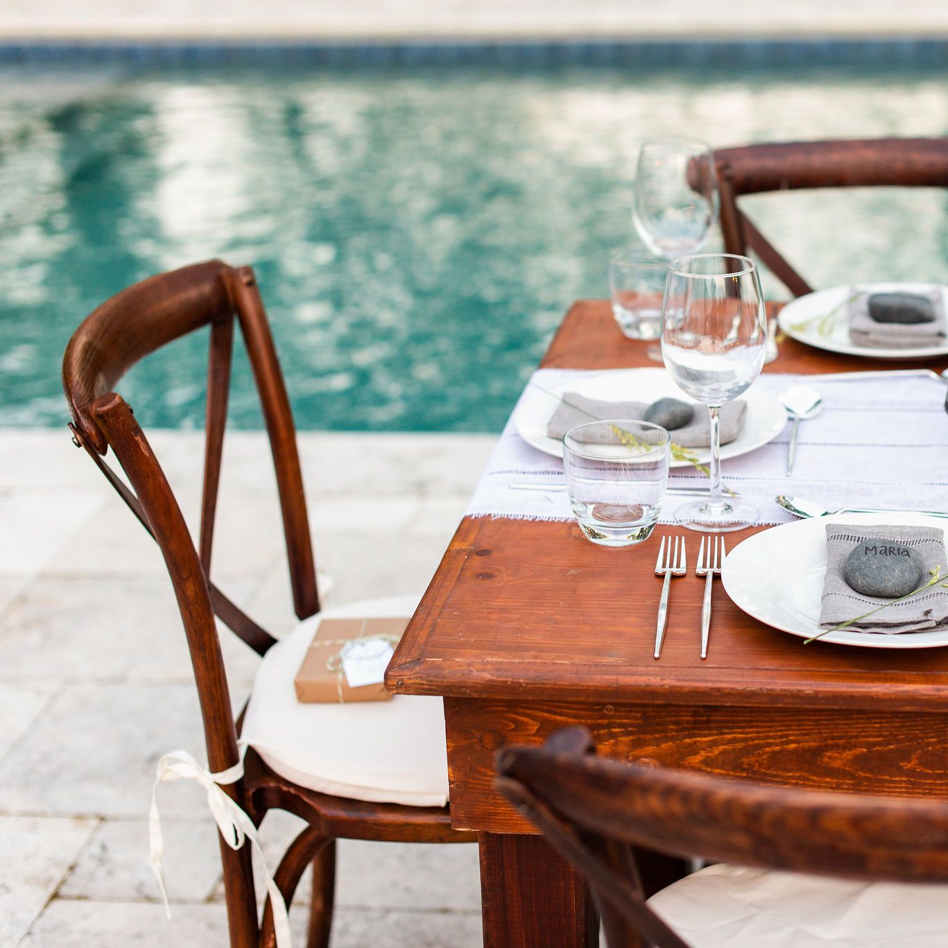 Elegant dining next to pool with travertine pool decking