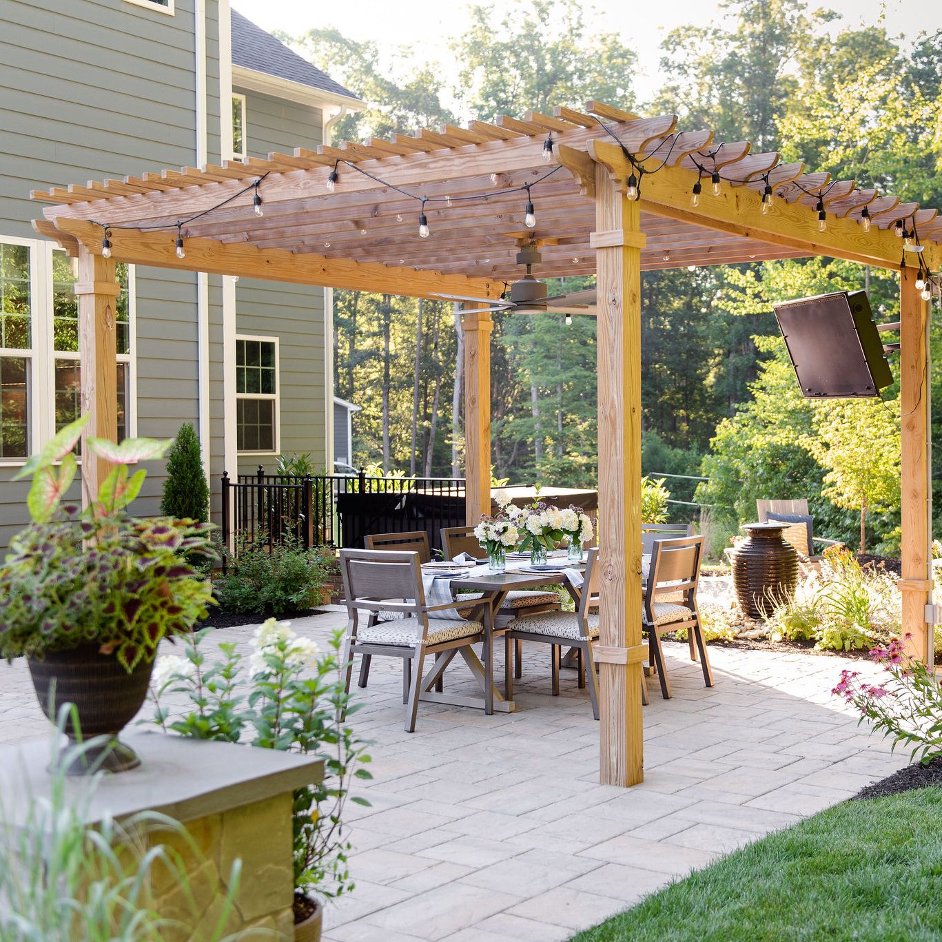 Pergola with outdoor television and bistro lights covering a dining area.