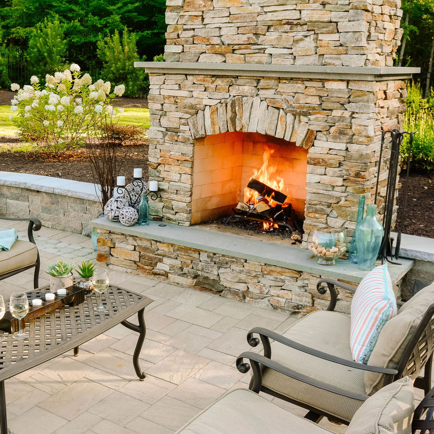 Stacked veneer stone outdoor fireplace on backyard patio