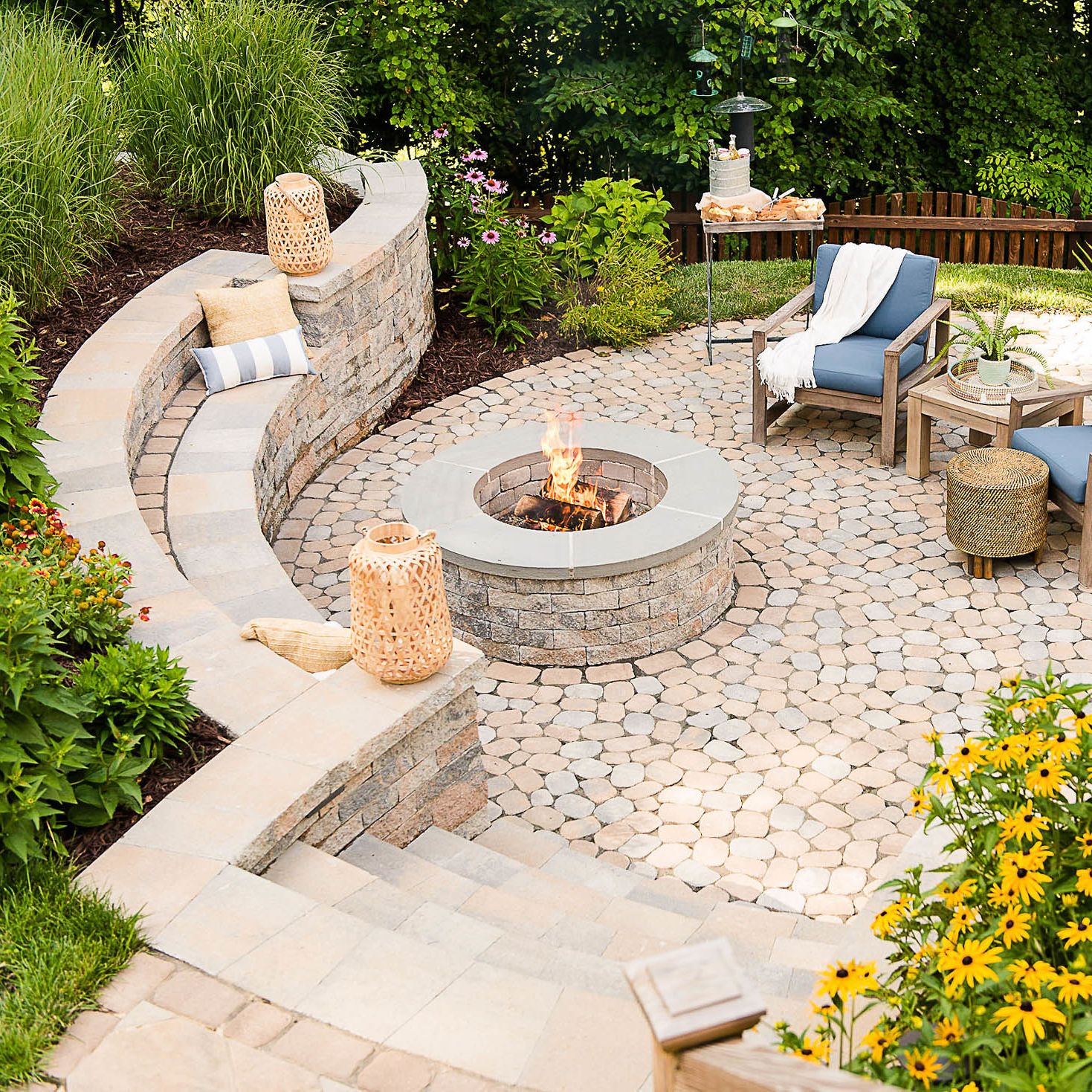 Stone steps lead down into paver patio to sit near the fire pit