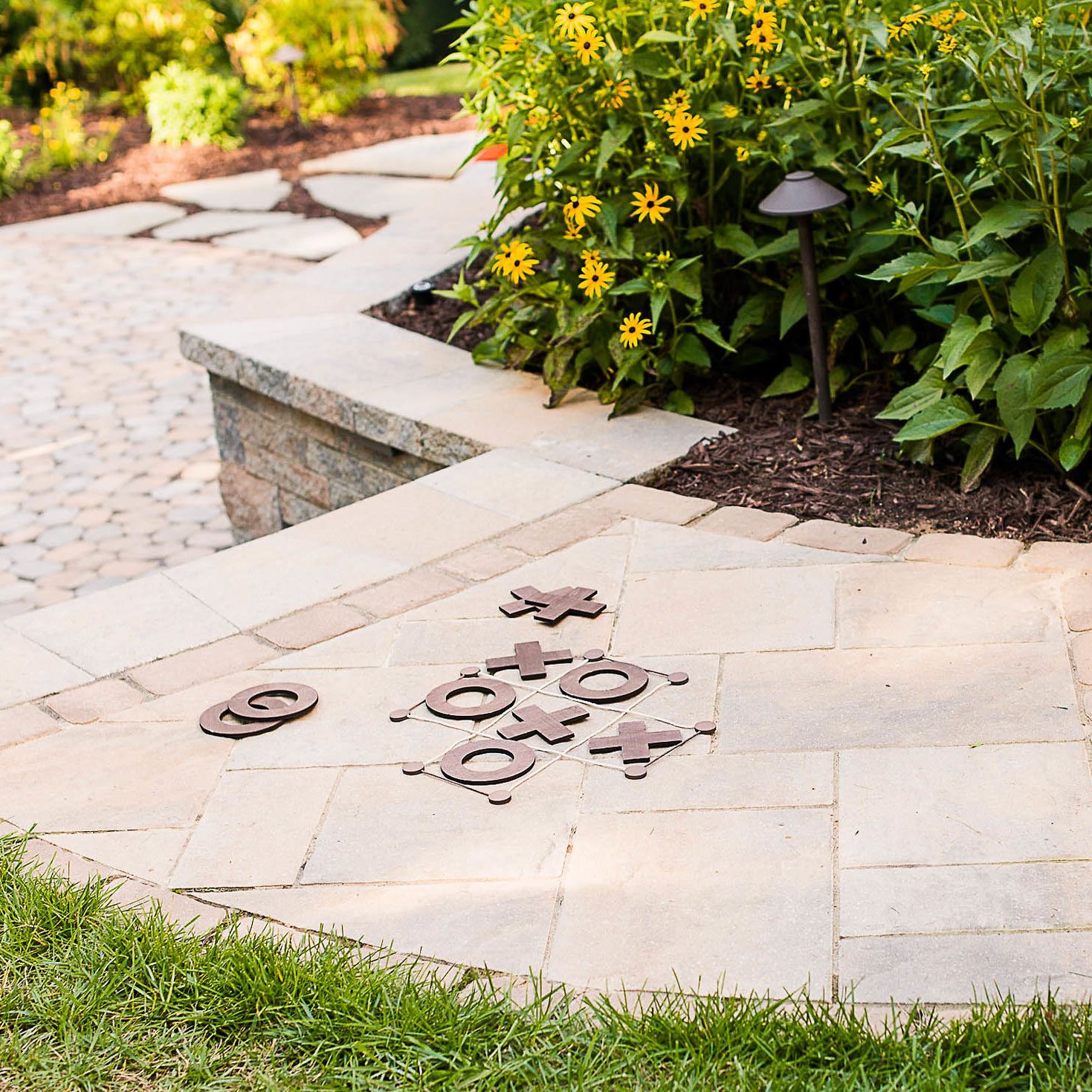 Tic Tac Toe game pieces on stone paver walkway