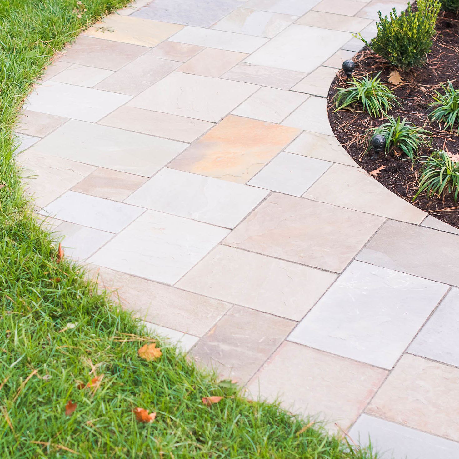 Paver path light-stone hardscape between lawn and landscaped mulched area