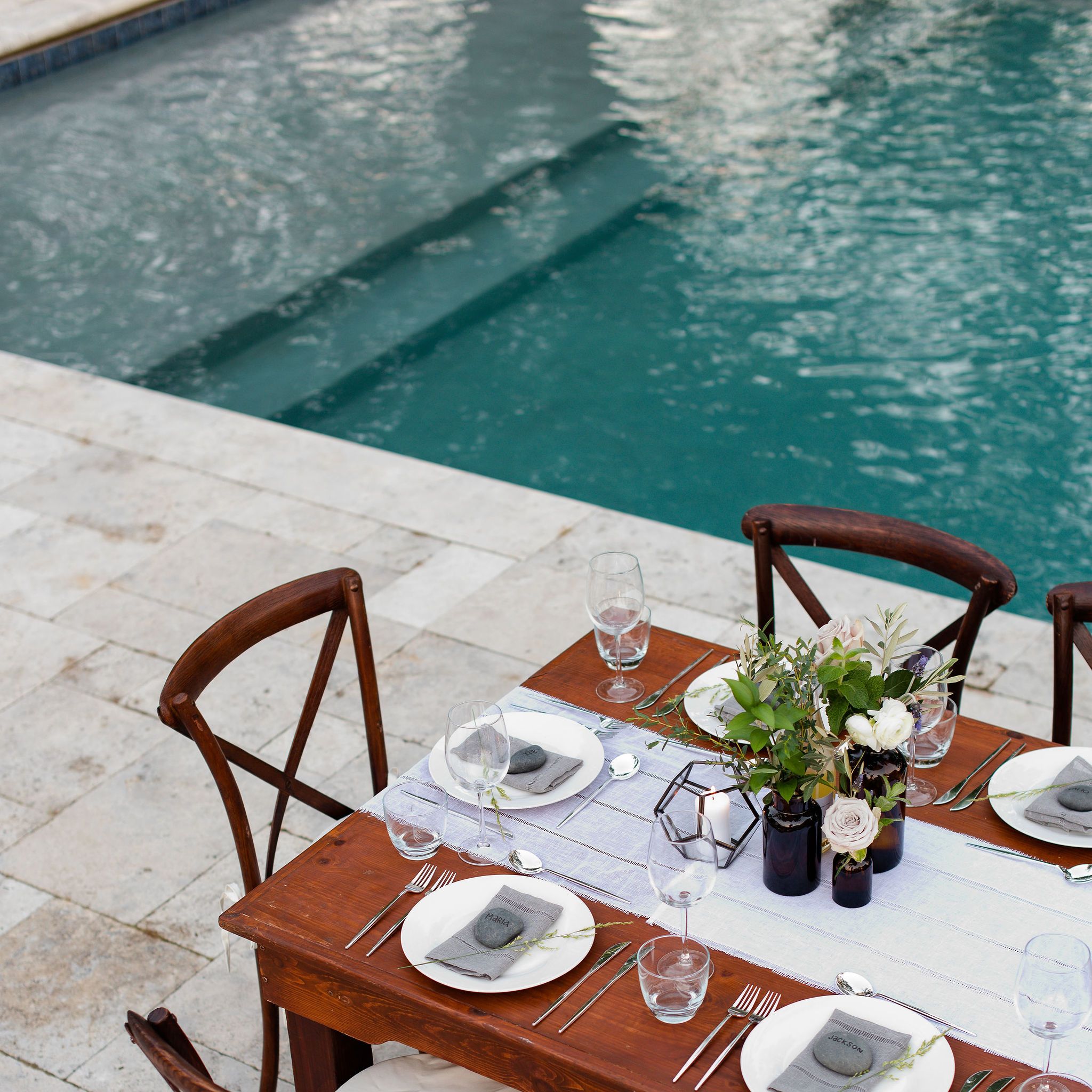 Elegant dining table on travertine patio with pool