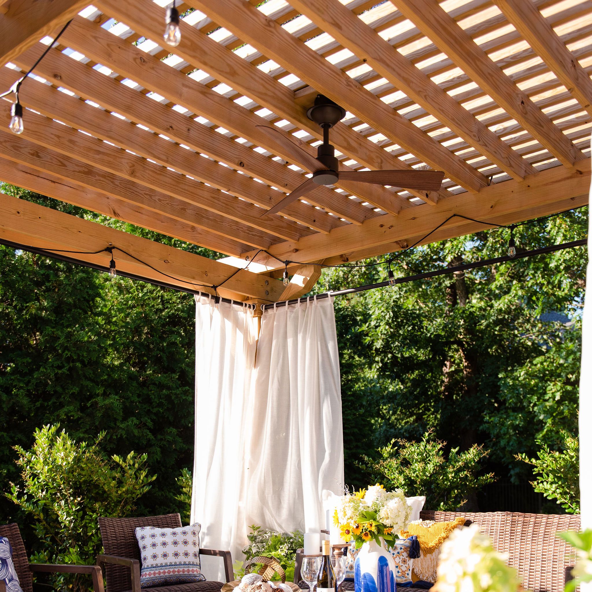 Pergola covered lounge area with a fan and curtains
