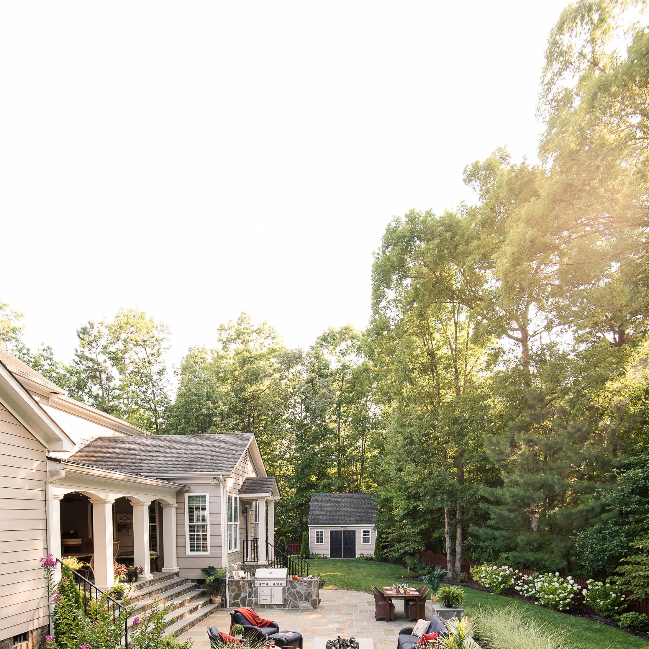 Spacious backyard landscape with lawn area, mulched section with tall wispy plants and patio
