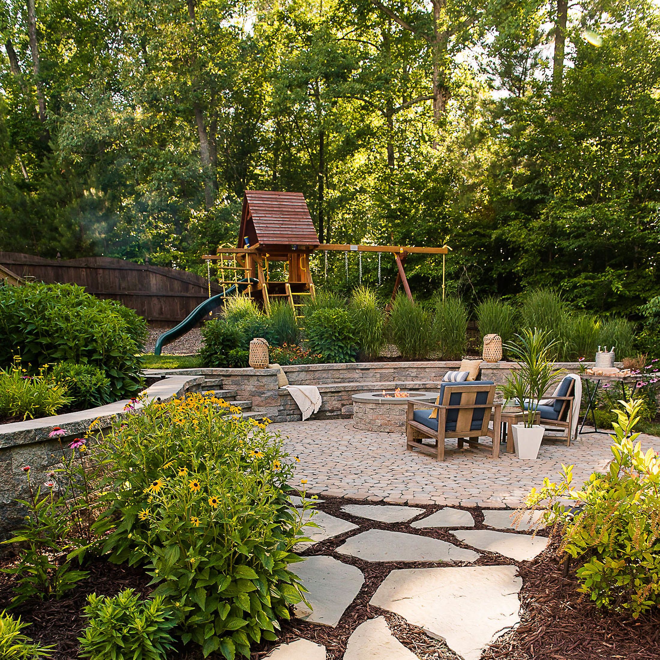 Natural stepping Stone walkway leading into circular  backyard paver patio and play set