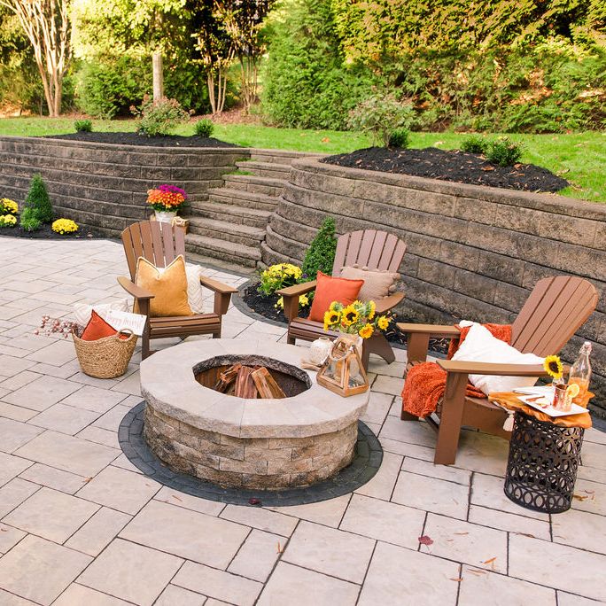 Outdoor patio hardscape with fire pit and retaining wall and steps leading to the yard